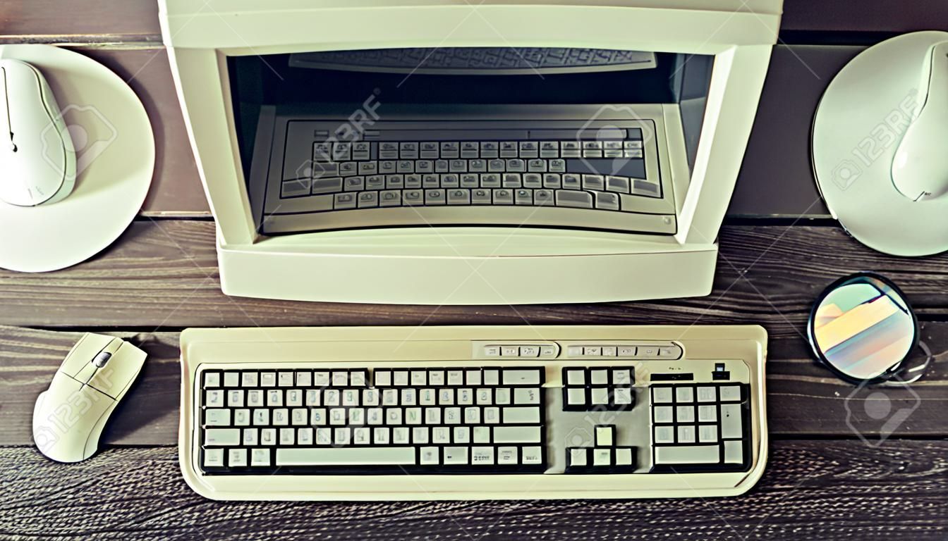 Computadora estacionaria retro en un escritorio de madera rústico, espacio de trabajo vintage. Monitor, teclado, mouse de computadora, vista superior, plano