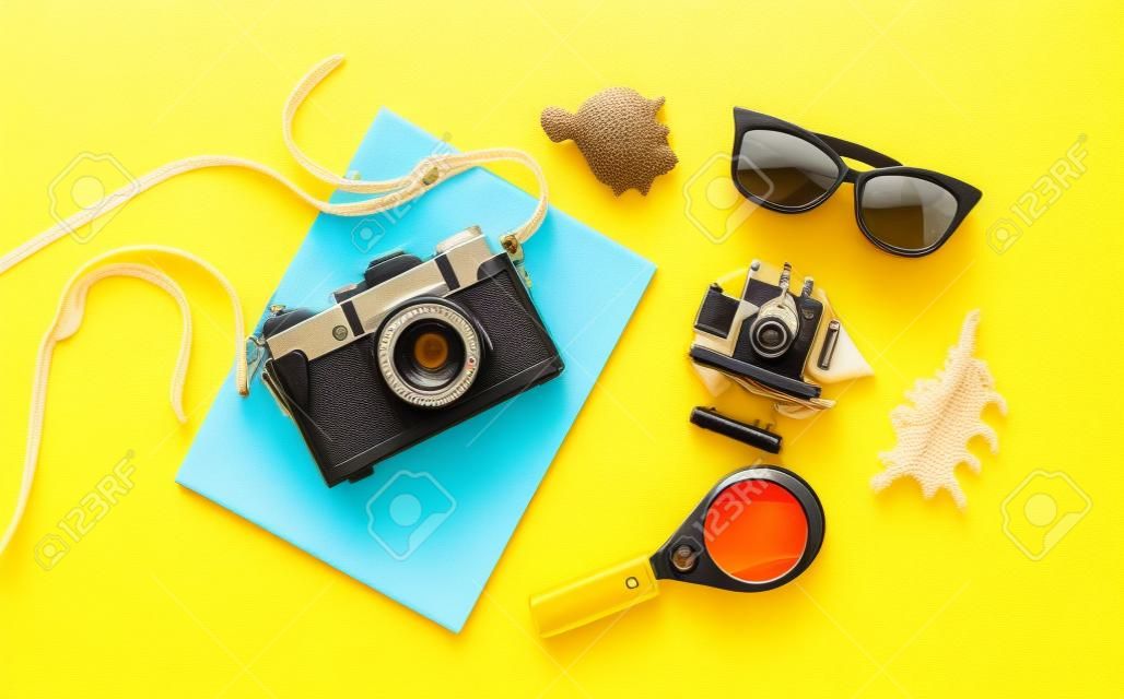Flaches Reisezubehör und Retro-Kamera auf gelbem Hintergrund. Sommerstrandhintergrund. Urlaubskonzept von oben