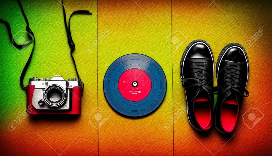 Retro still life. Old fashioned sneakers, vinyl record,  vintage film camera on colored background. Top view. Pop art flat lay