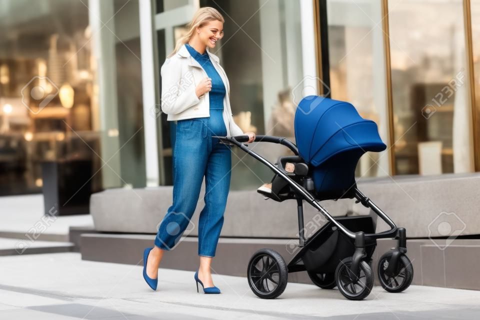 Stylish loving mom walks with a stroller in the city location. Maternity, lifestyle