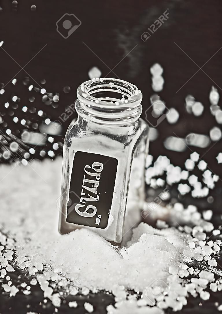 sprinkled salt shakers of white salt on the black background