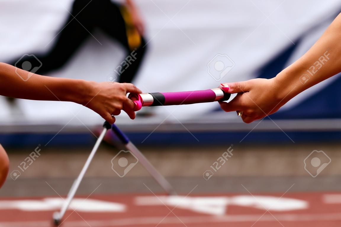 women team relay race passing of baton on stage