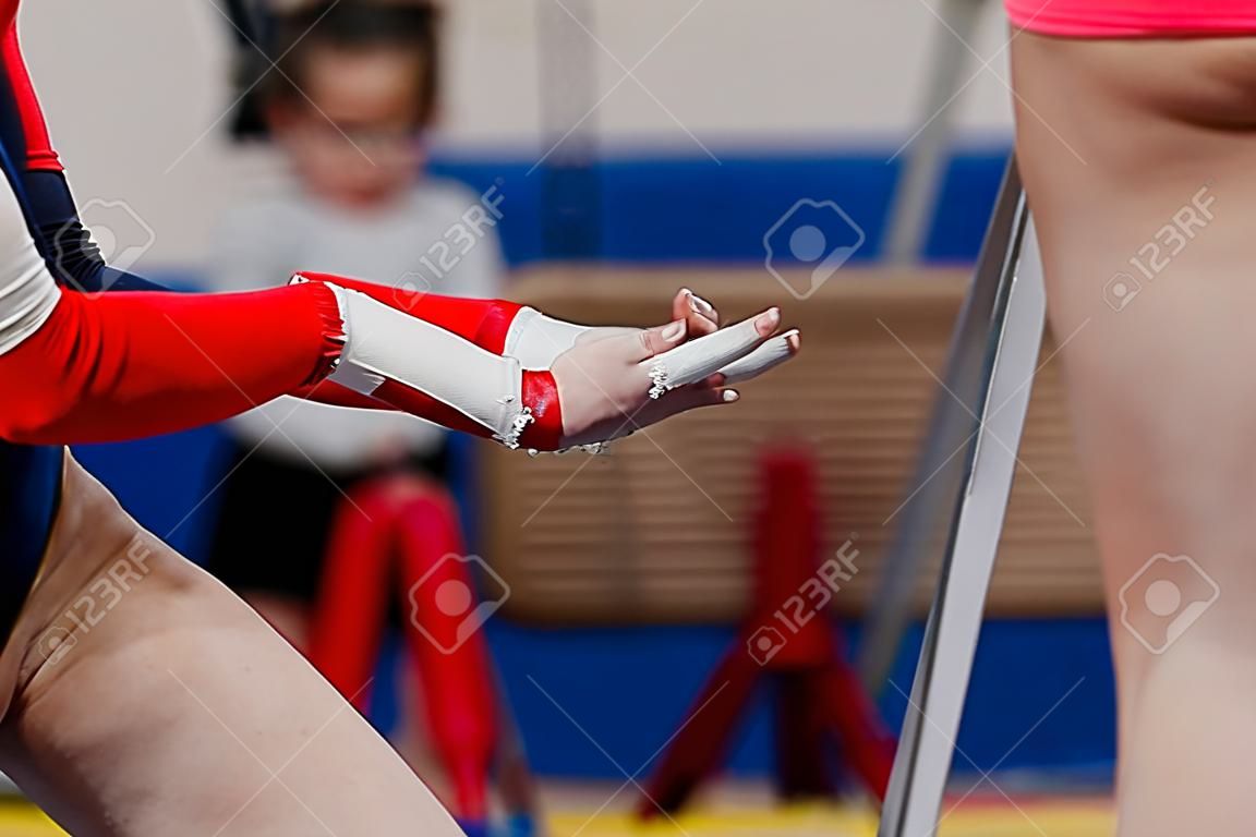 ginnasta ragazza in manopole di ginnastica e gesso da palestra