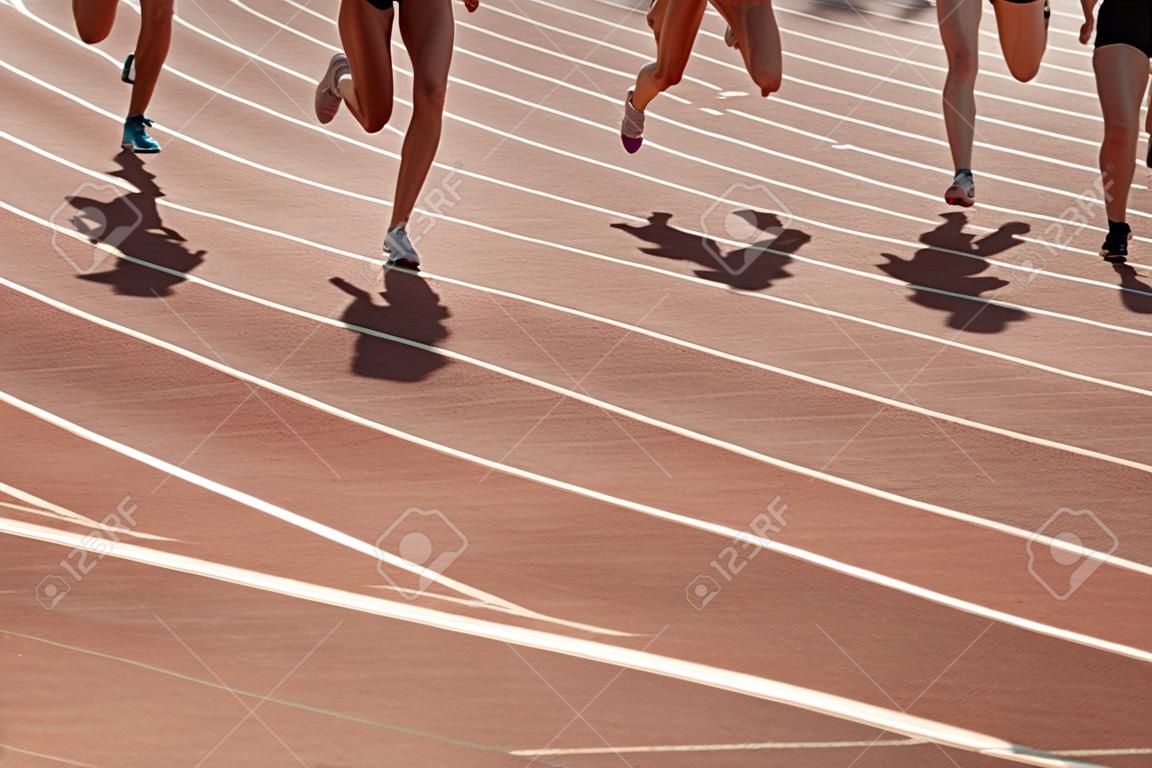 경기장 트랙을 달리는 그룹 여성 운동선수