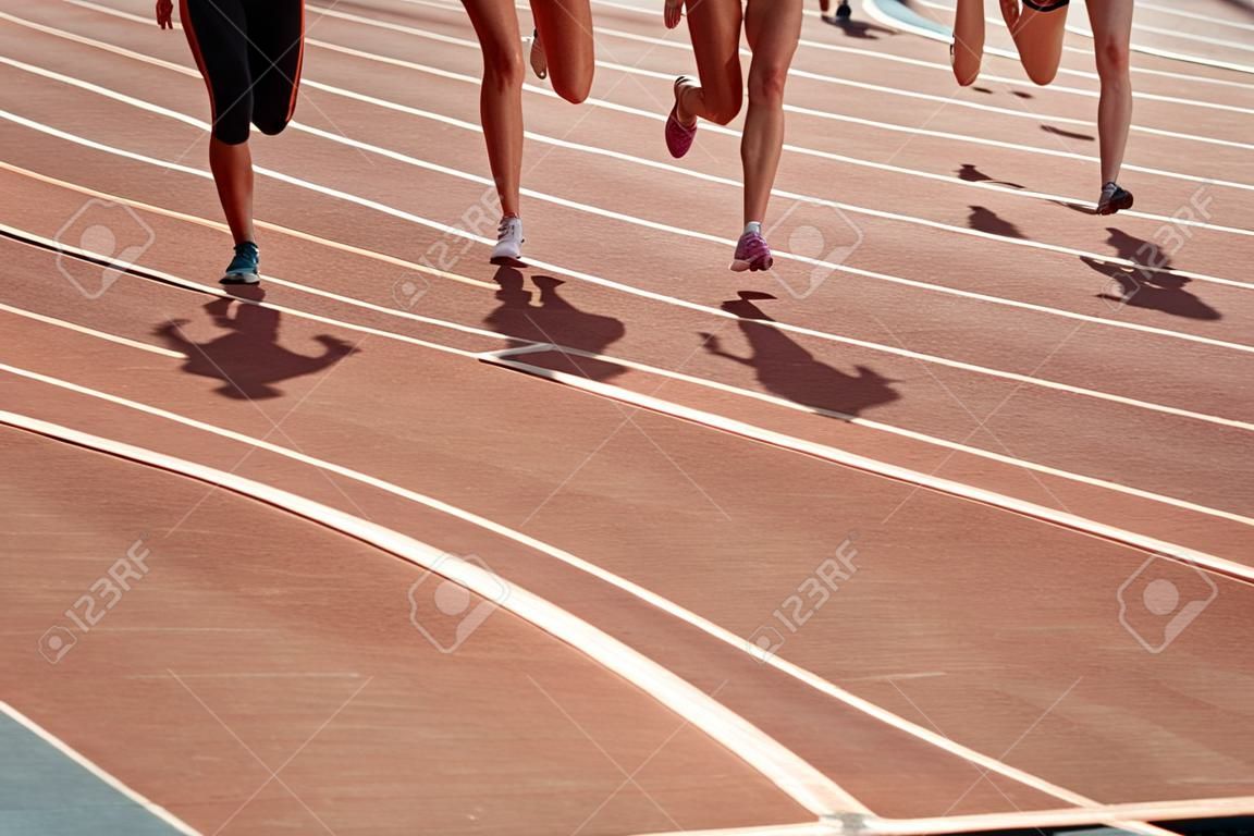 group female athletes running track of stadium