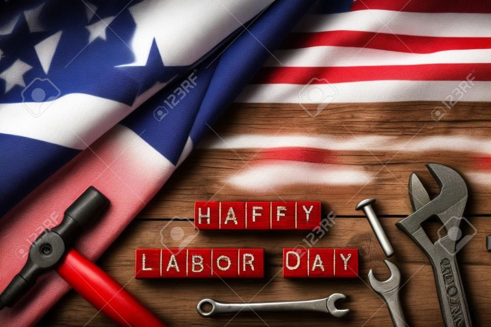 USA Labor day concept, First Monday in September. Different kinds on wrenches, handy tools, America flag and wooden blocks on wooden table.