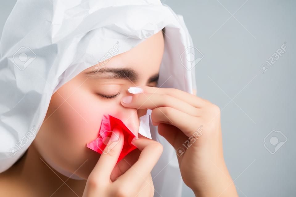 Hemorragia nasal, una mujer joven que sufre hemorragia nasal y utiliza papel tisú para detener la hemorragia. Salud y concepto médico.