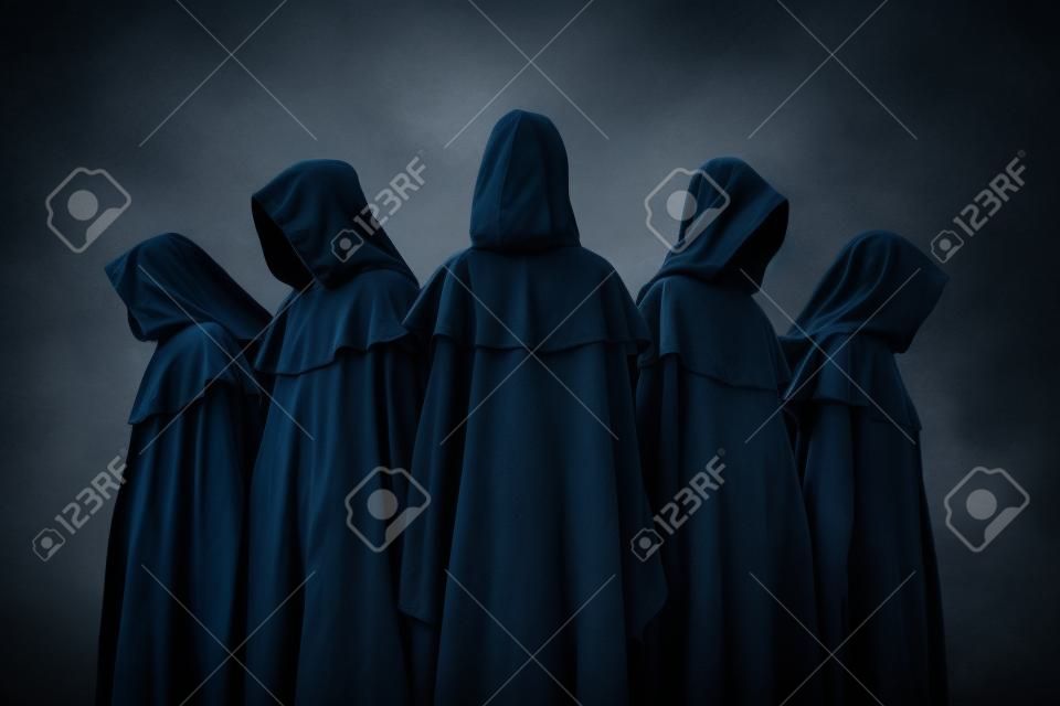 Group of five scary figures in hooded cloaks in the dark