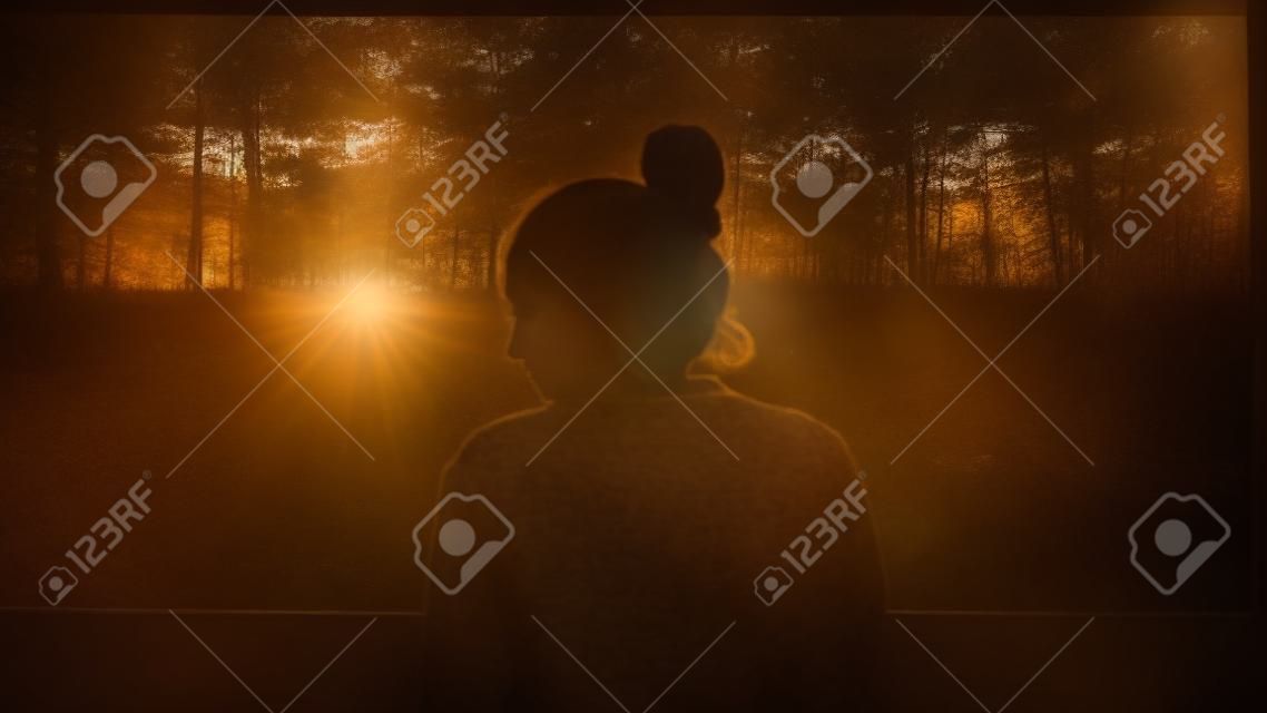 Silhouette of young beautiful girl in the village. Model on background of a forest. Woman girl in front of the window.
