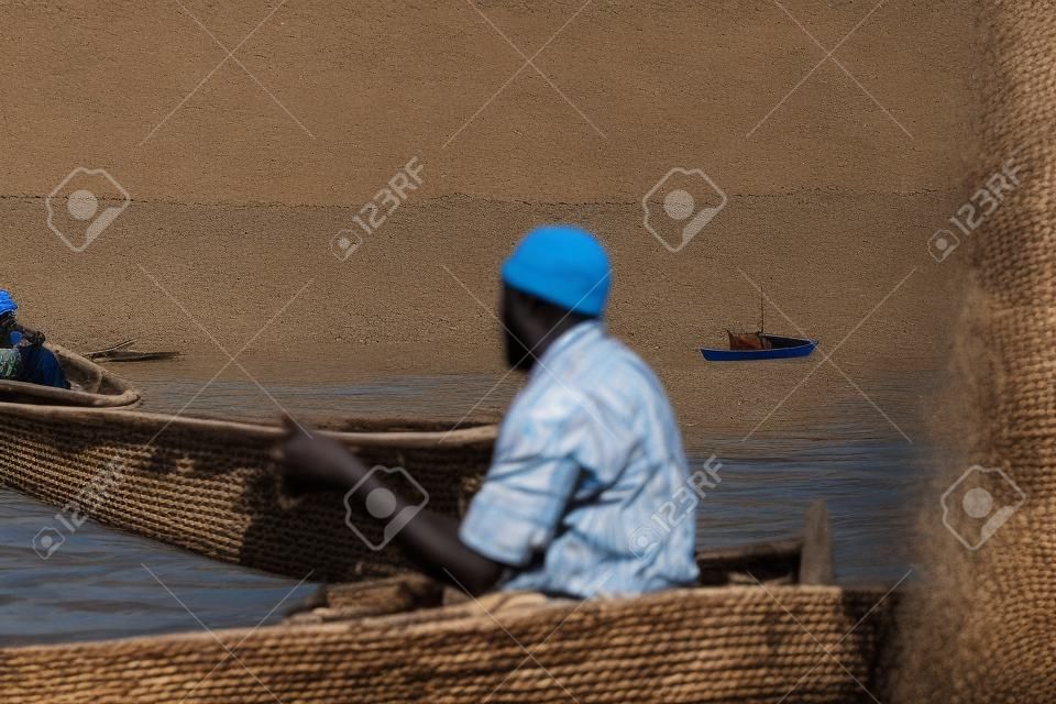 Hombres africanos sentados en el bote. Hombres trabajando, pescando. Negocios de la población local en África.