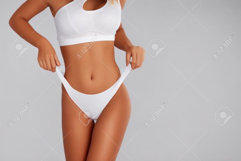 Vrouwelijk lichaam in wit ondergoed op de witte achtergrond.