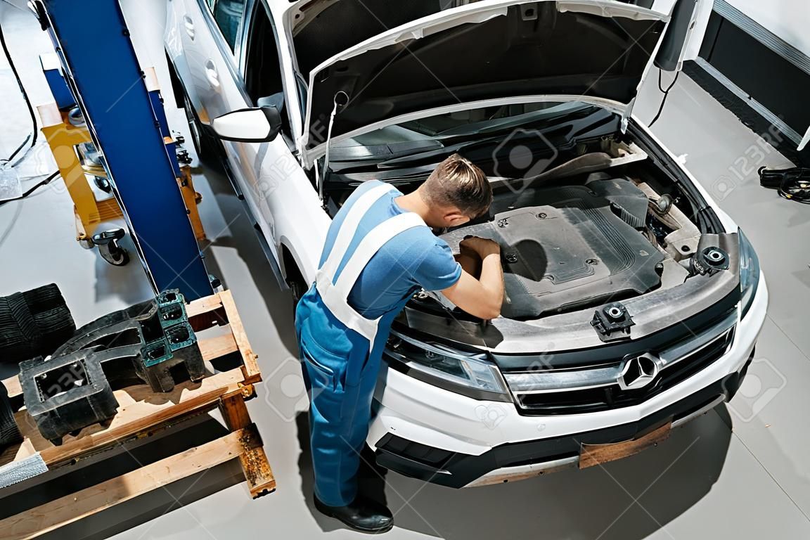 Aerial view. Employee in the blue colored uniform works in the automobile salon.