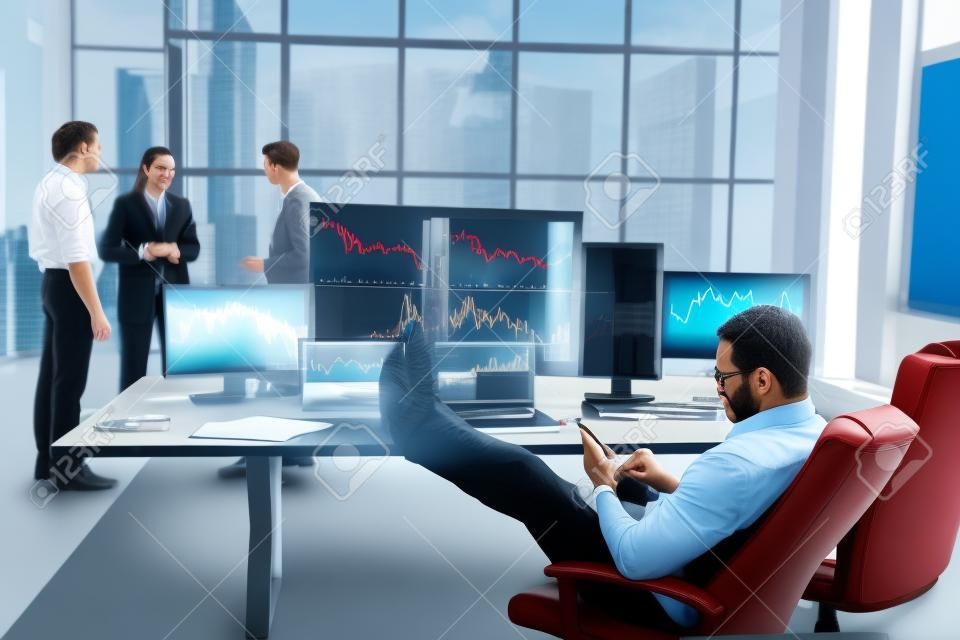 Man sits on chair and takes break. Team of stockbrokers works in modern office with many display screens