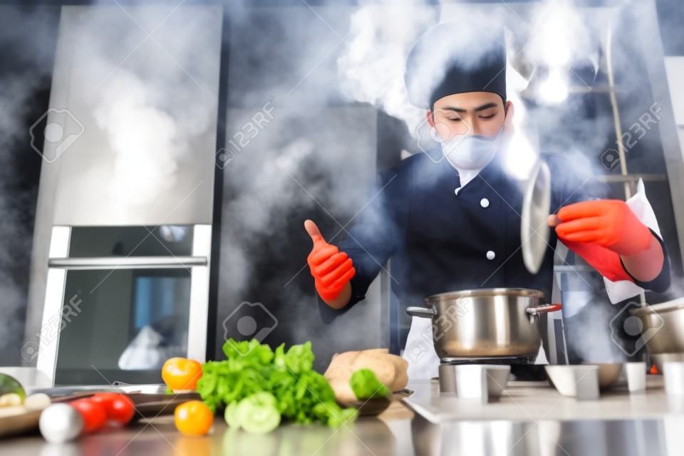 Processus de préparation. jeune chef cuisinier professionnel en uniforme travaillant dans la cuisine