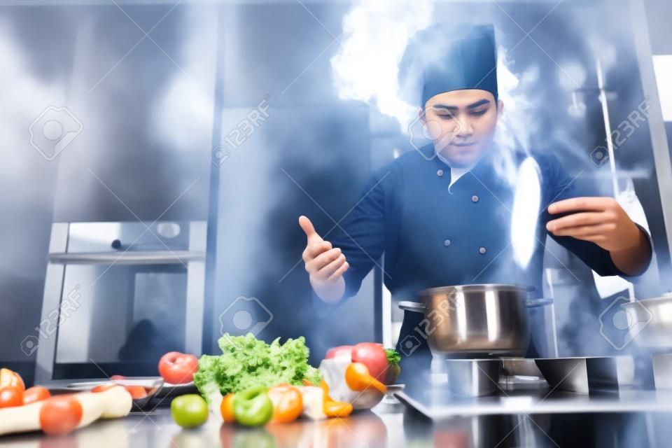 Processus de préparation. jeune chef cuisinier professionnel en uniforme travaillant dans la cuisine