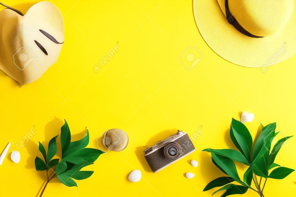 Draufsicht und flacher gelber Hintergrund für Sommerferien, Fotokamera, Hut, Palmblatt. Platz kopieren.