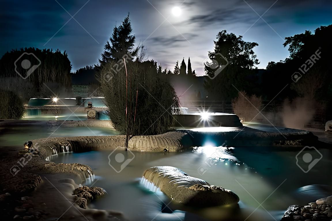 Vista noturna do famoso spa gratuito do moinho em Saturnia, na Toscana, Itália. Uma série de piscinas naturais de água quente onde as pessoas relaxam
