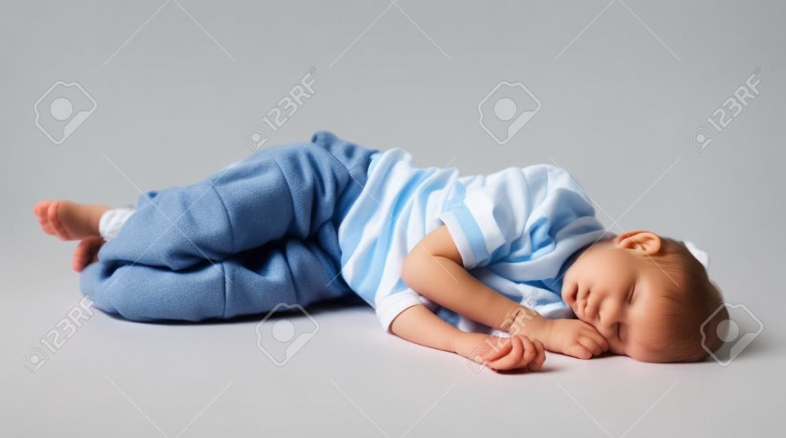 Fáradt, kimerült gyermek alszik a földön, elszigetelt fehér háttér