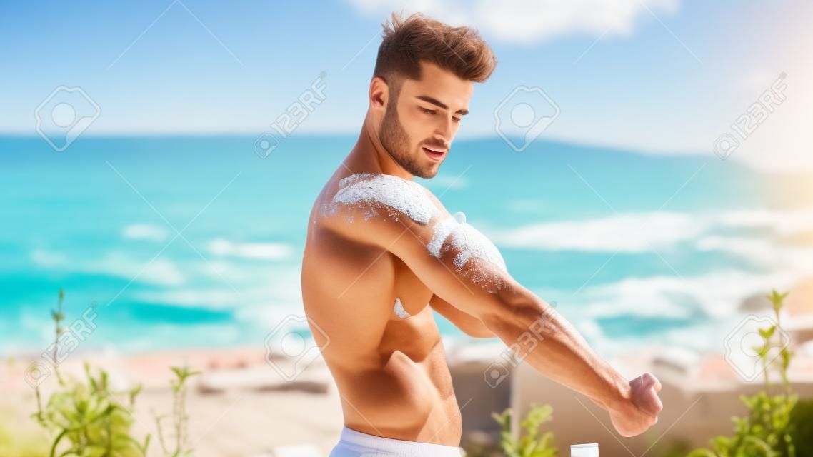 Hemdloser junger Mann, der Sonnencreme aufsetzt, muskulöser Mann im Badeanzug, bereit zum Sonnenbaden auf der Terrasse