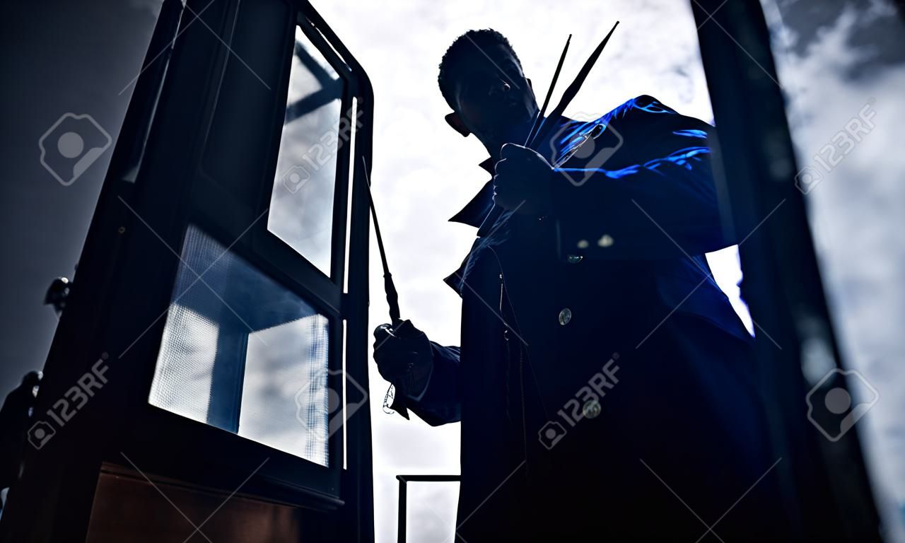 Silhouette of man in image of black magician with magic wand in his hand. Closeup.