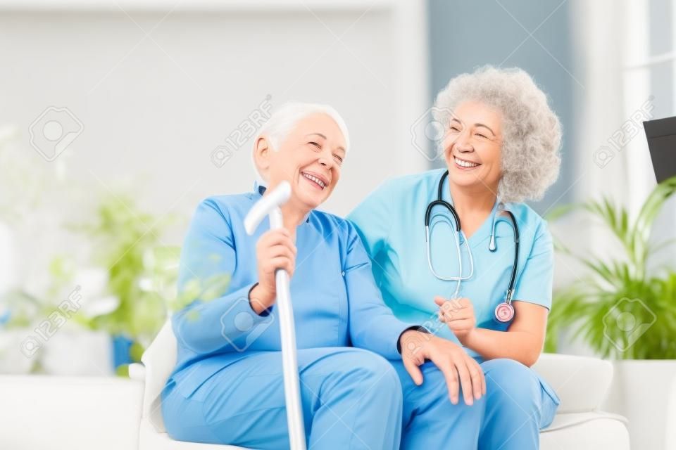 Rapporto amichevole tra badante sorridente in uniforme e donna anziana felice. giovane infermiera solidale che guarda la donna anziana. giovane badante adorabile premuroso e reparto felice