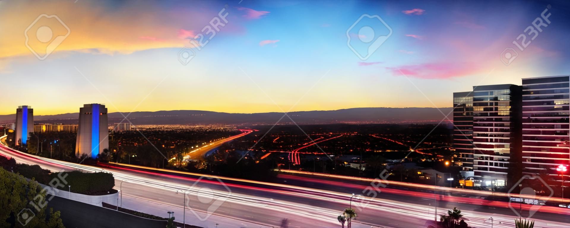 Wschód słońca nad autostradą w Irvine w Kalifornii, gdy ślady reflektorów poruszają się po drogach.