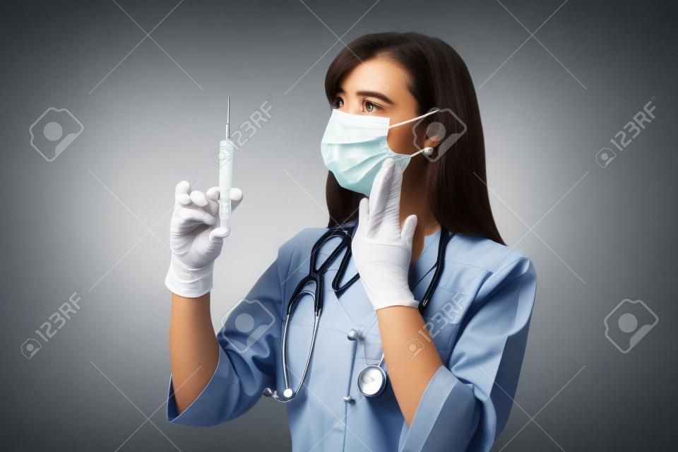 Doktor mit einer Spritze auf einem grauen Hintergrund