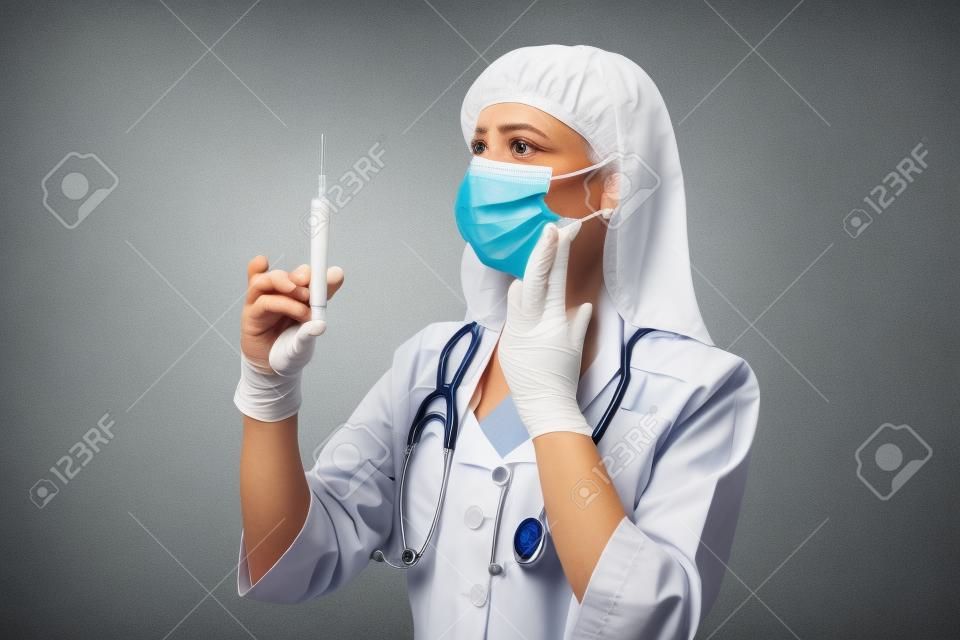 Doktor mit einer Spritze auf einem grauen Hintergrund