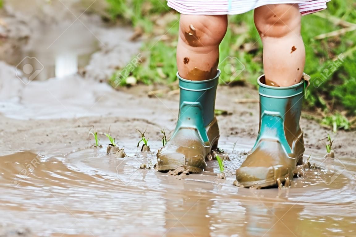 孩子的腳踩在泥濘的水坑里。
