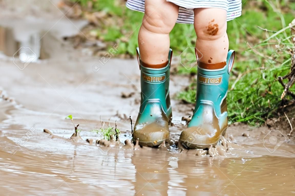 孩子的腳踩在泥濘的水坑里。