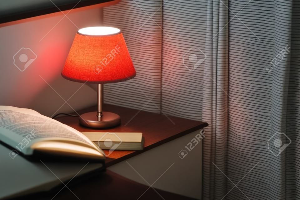 Lampa elektryczna i książka na stoliku nocnym w sypialni, selektywna ostrość