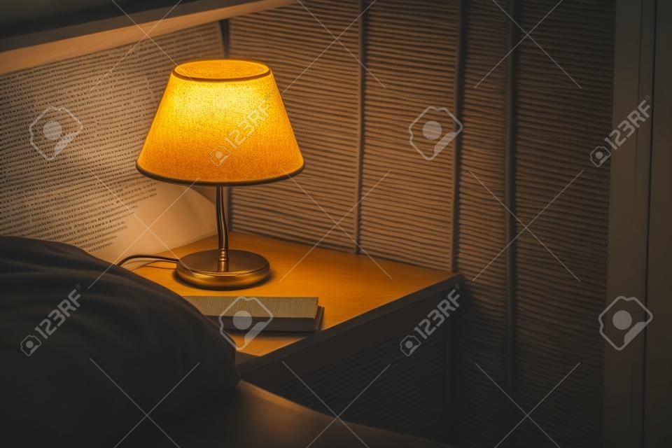 Lampa elektryczna i książka na stoliku nocnym w sypialni, selektywna ostrość