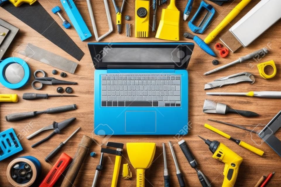 Laptop egy munkaasztal DIY és építőipari eszközök körül, felülnézet, hobby és kézműves koncepció