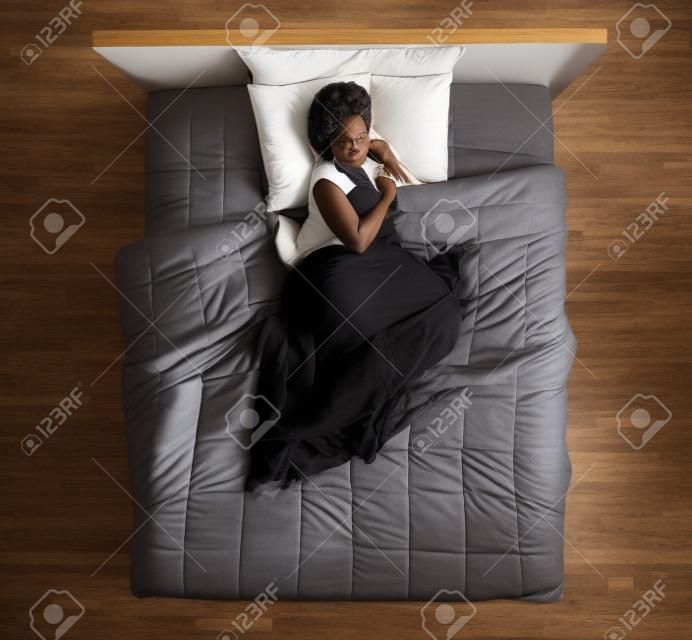 Beautiful african american woman lying in bed and sleeping, top view