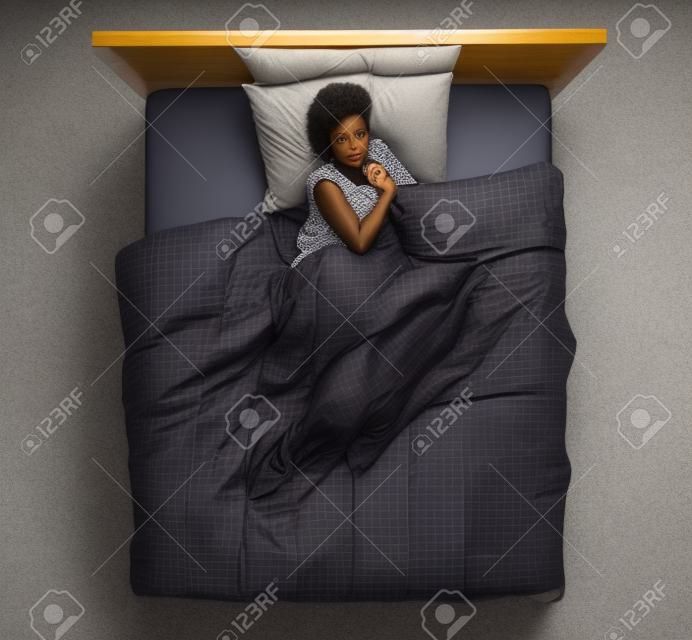 Piękna afroamerykanka leżąca w łóżku i śpiąca, widok z góry