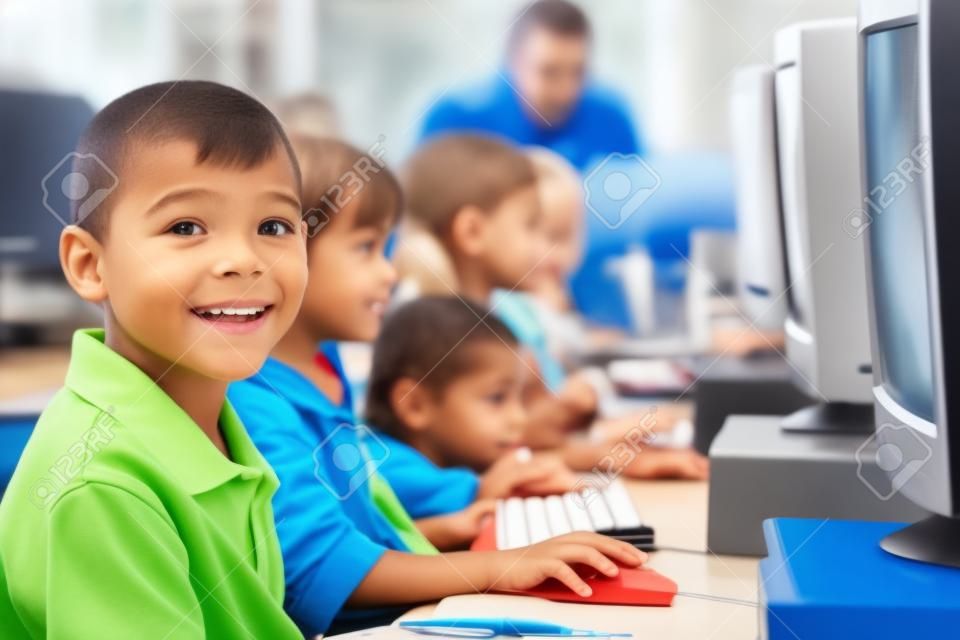 Los niños a terminales de computadora con el maestro en el fondo (profundidad de campo / clave de alta)