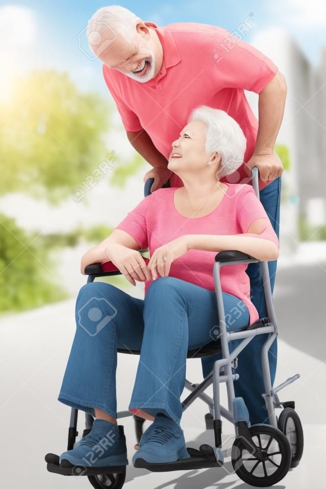 Senior vrouw duwen ongelukkige echtgenoot in rolstoel