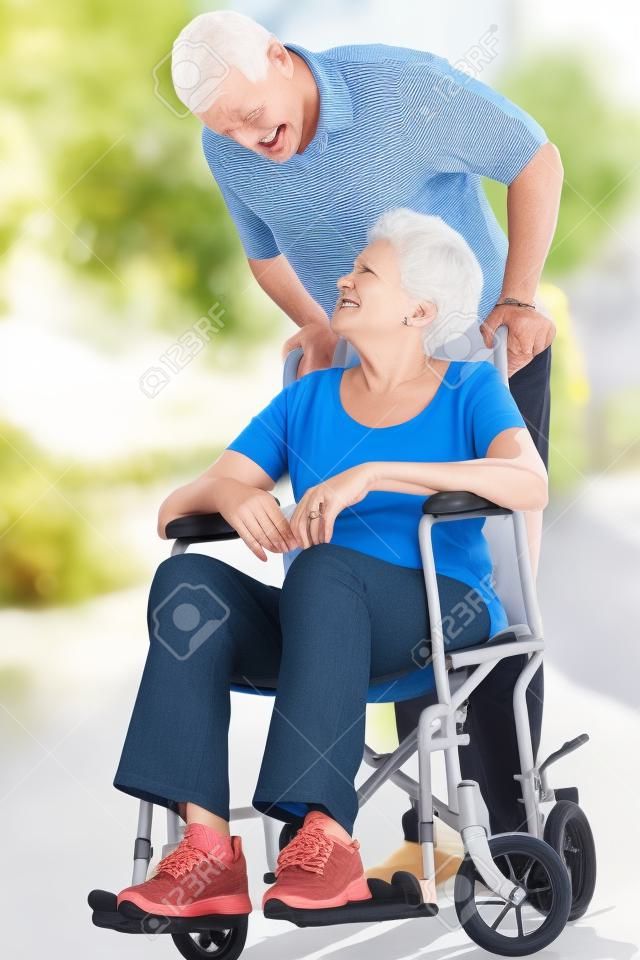 Senior vrouw duwen ongelukkige echtgenoot in rolstoel