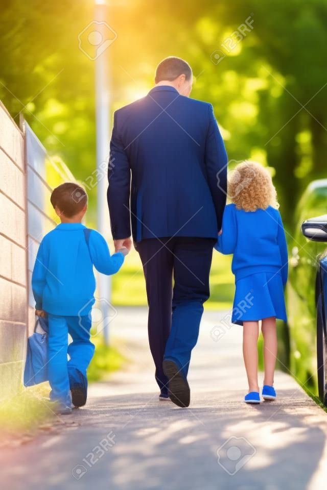 Padre que recorre a la escuela con los niños en camino a su trabajo