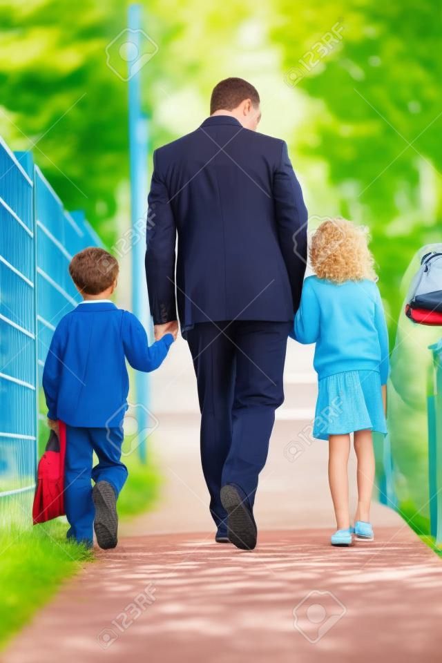 Padre que recorre a la escuela con los niños en camino a su trabajo