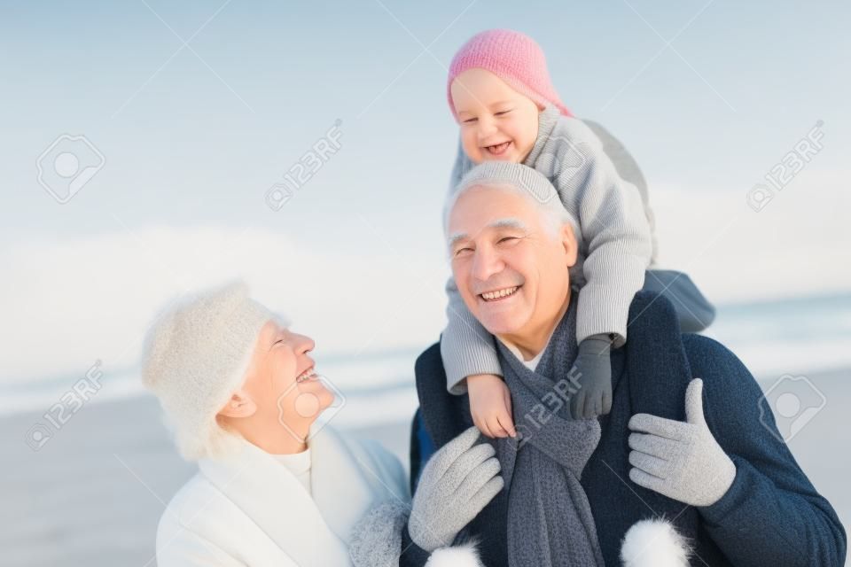 祖父母和孙女在冬季海滩散步