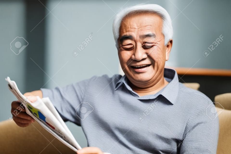 Homem asiático sênior que lê o jornal