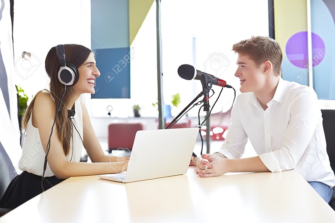 Jonge vrouw interviewt een gast in een studio voor een podcast