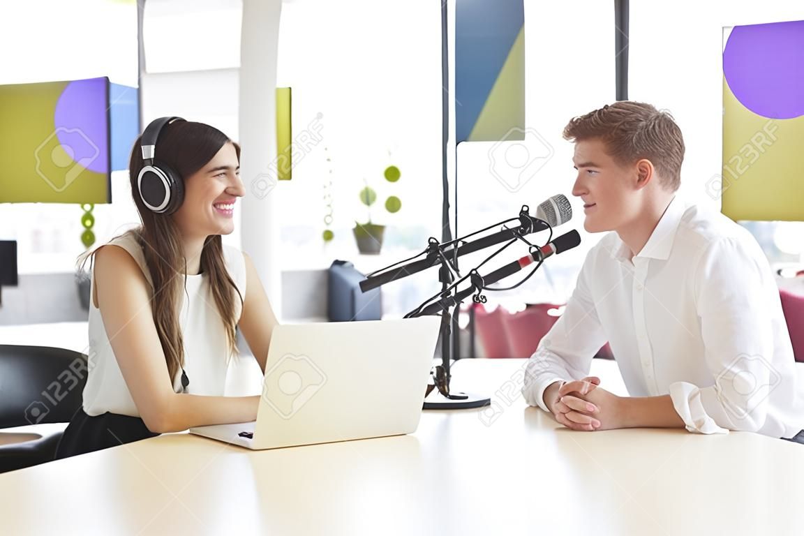 Jonge vrouw interviewt een gast in een studio voor een podcast
