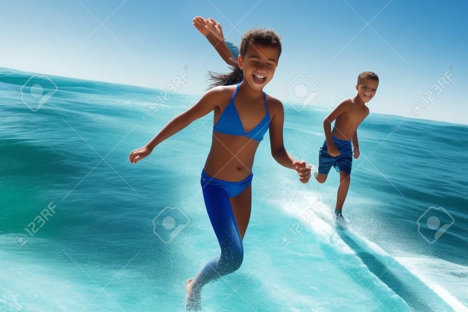 Garçon et fille en vacances d'été qui traverse les vagues