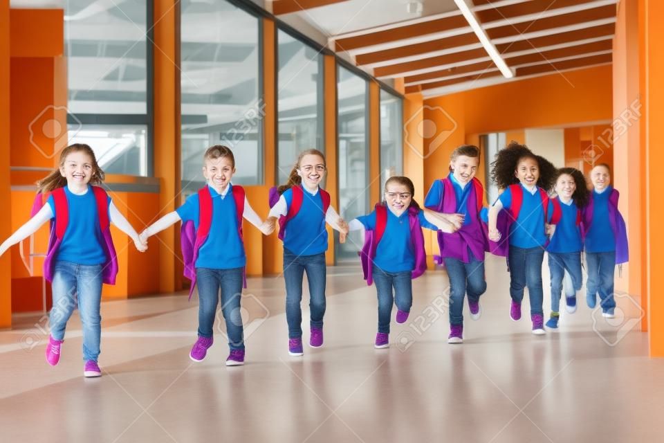 Les enfants de l'école primaire courent main dans la main dans le couloir, gros plan