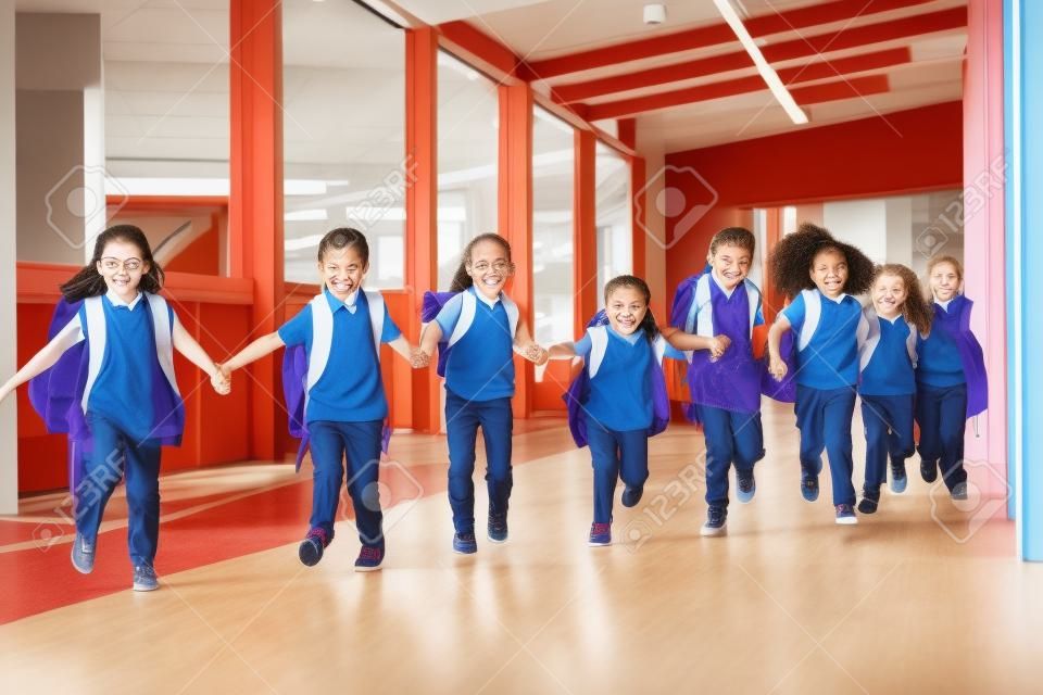 Primary school kids run holding hands in corridor, close up