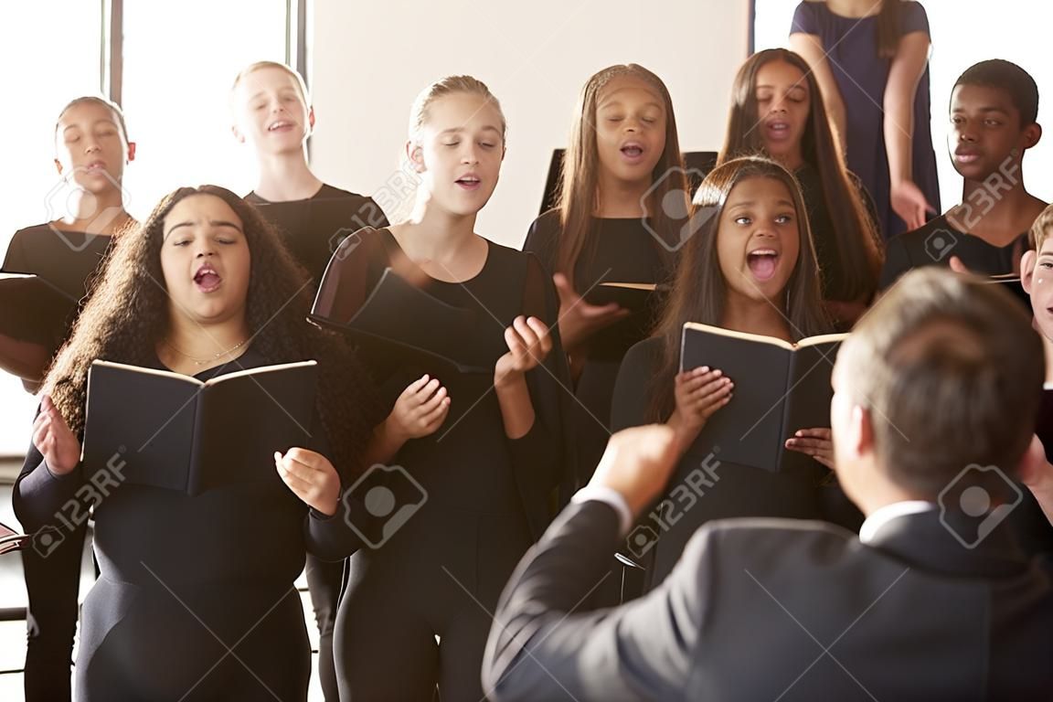 Mannelijke en vrouwelijke studenten zingen in koor met leraar op Performing Arts School