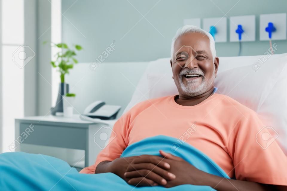 Retrato de paciente senior masculino acostado en la cama de un hospital sonriendo a la cámara