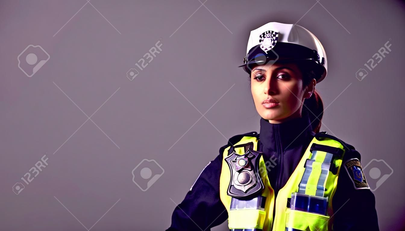 Retrato de estudio de una joven policía seria contra un fondo liso